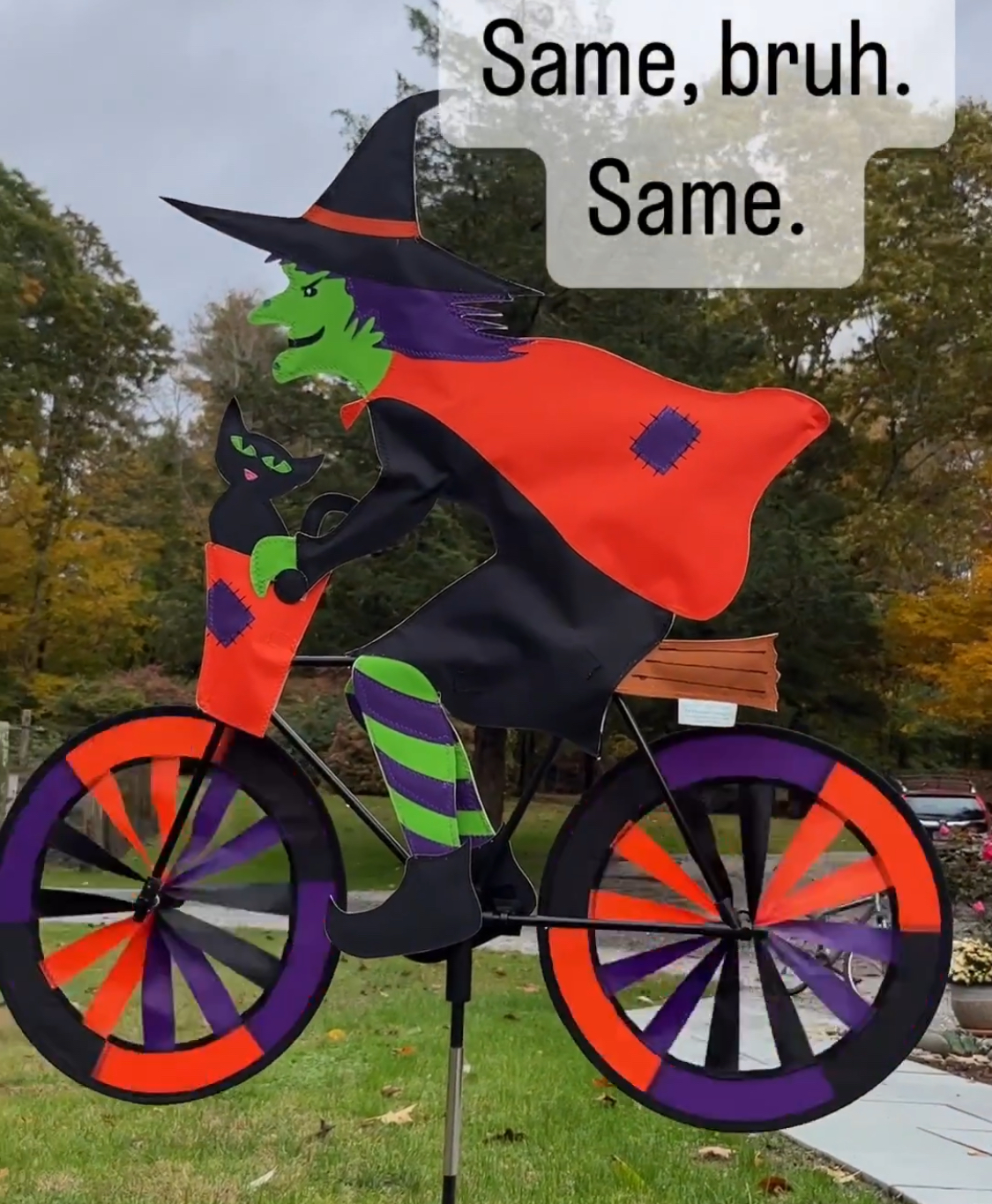 A yard sign of a Halloween witch on a bike, of which the wheels turn in the wind, making the witch seem to be riding the bike.