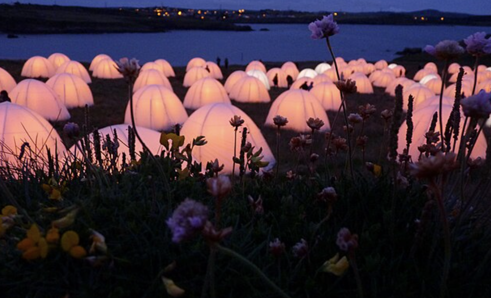 Image of pink glowing orb tents placed in a British seaside field.