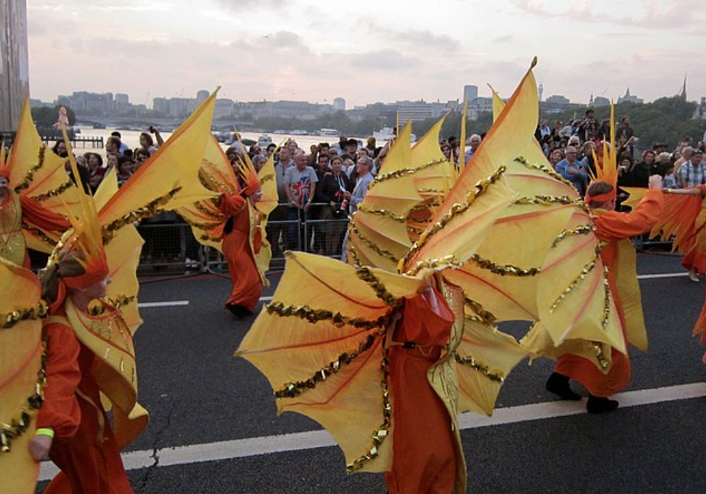 Photograph of five participants costumed like human "flames" marching in the Cultural Olympiad Carnaval in London, 2012.