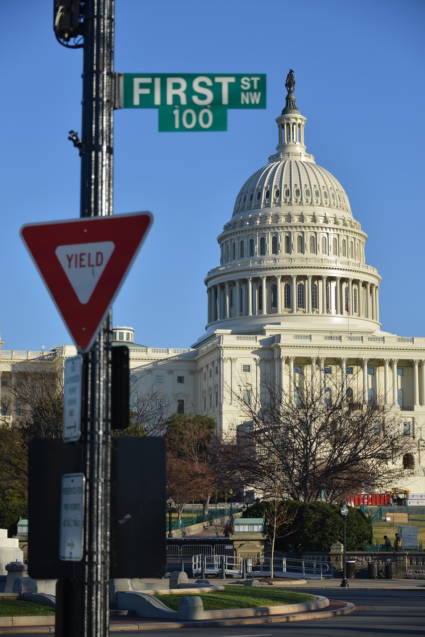 The U.S. Capitol Building, as seen from a street, with street signs saying "Yield" and "100 First Street" in the foreground.